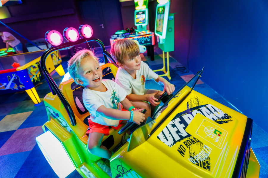 Two children playing an arcade game while having fun